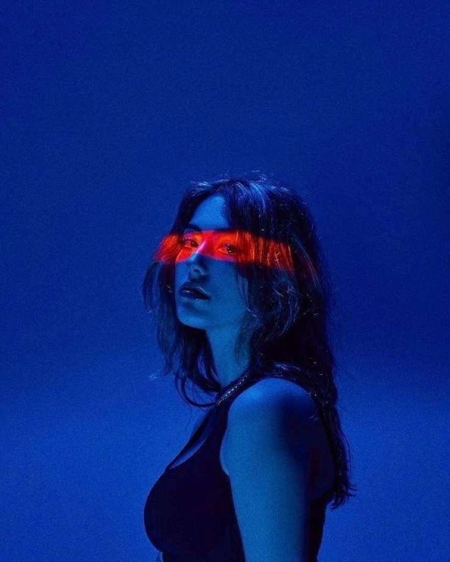 Retrato de artista bañado en luz azul con una franja de luz roja sobre los ojos.