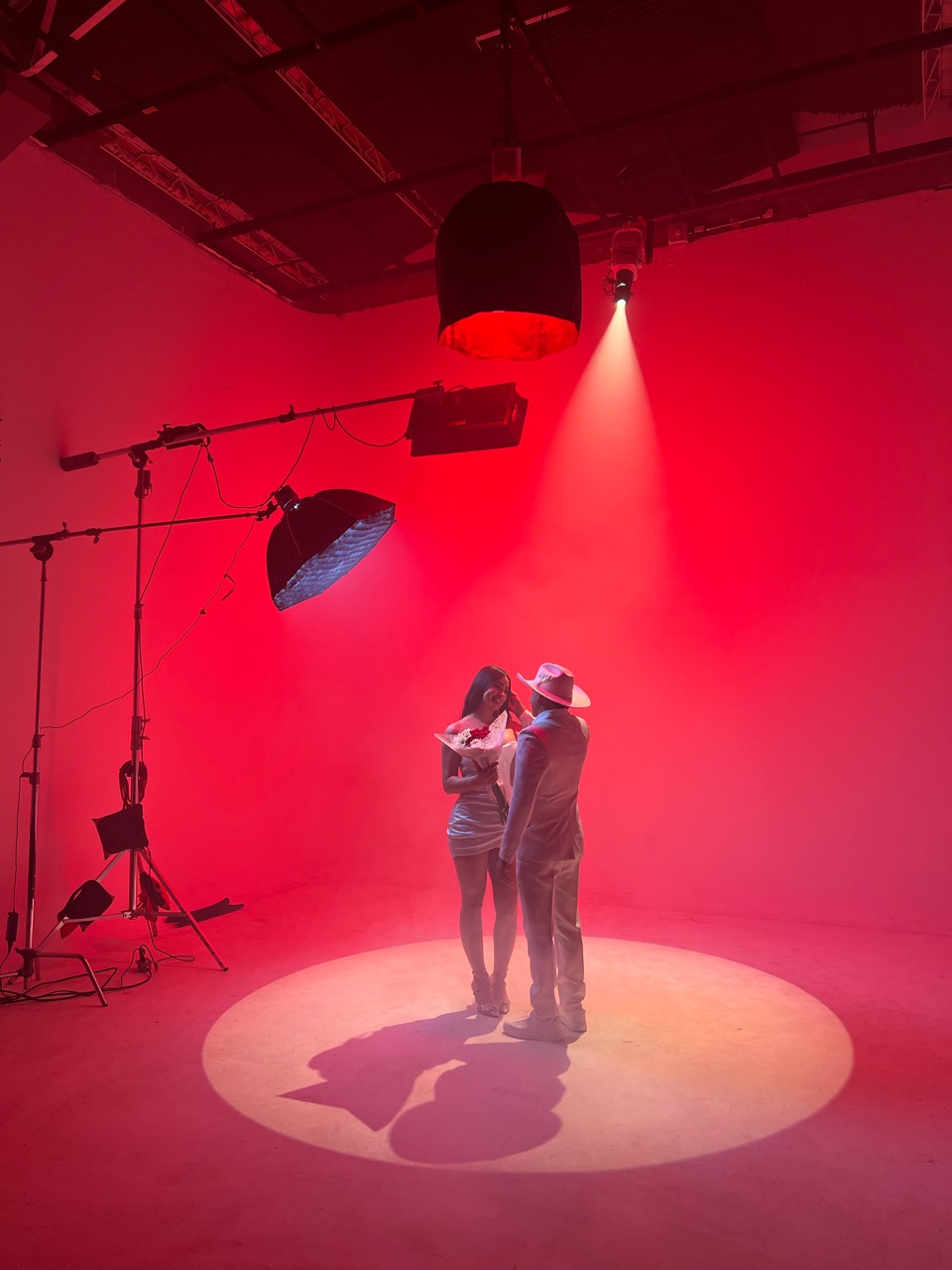Pareja dentro de un círculo de luz rodeada por una atmósfera roja de estudio.